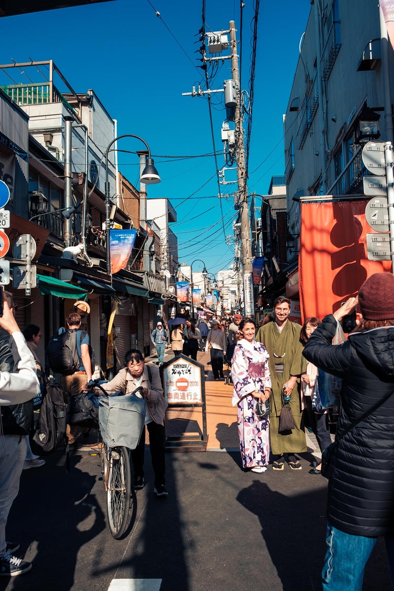 Tourists take a picture with tipical Japanese dresses while a local tries to pass.