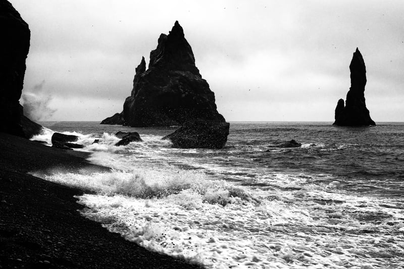 Waves crash violently onto the black beach